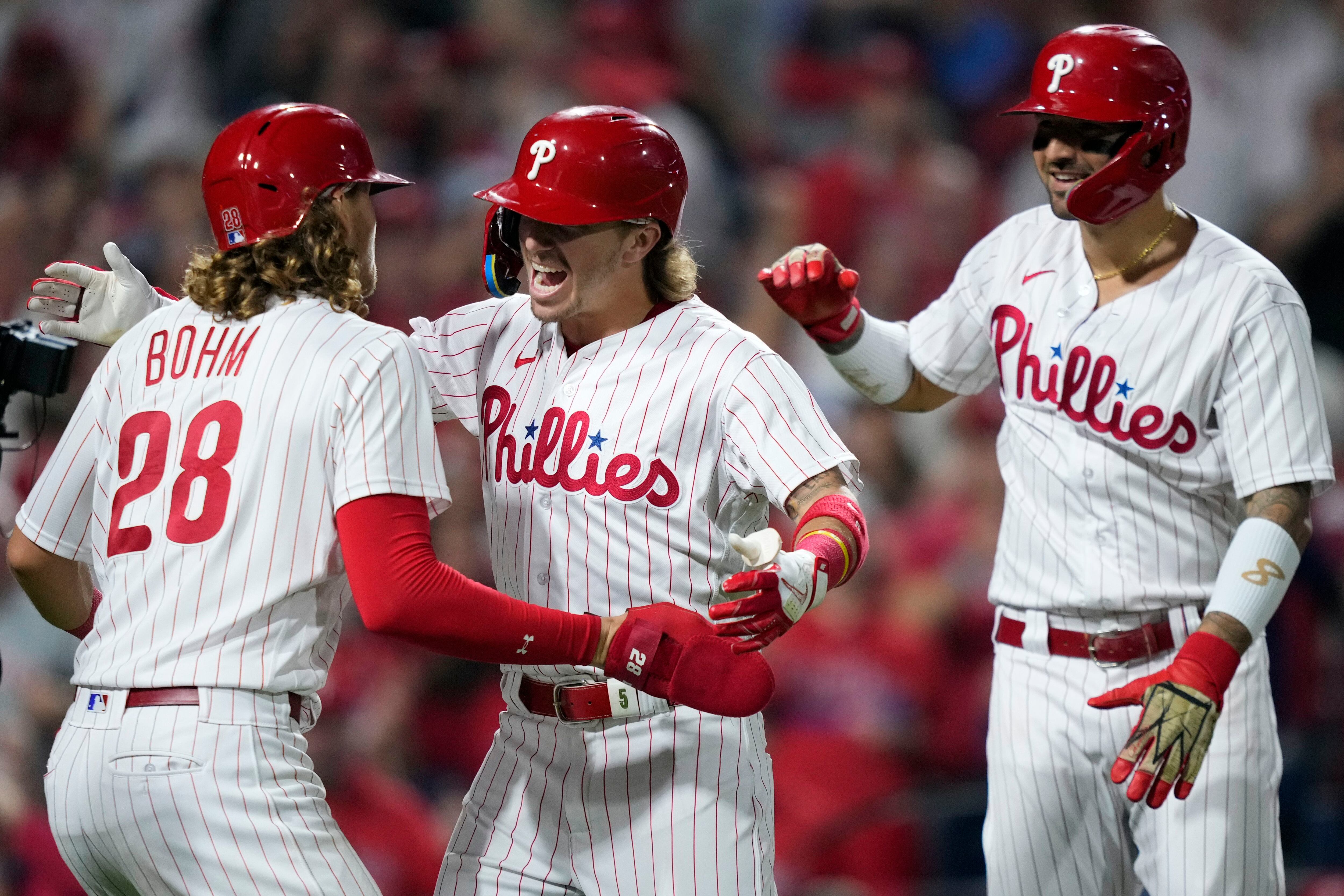 Philadelphia Phillies - The team celebrating winning today's game. They are  wearing white Phillies uniforms and hugging Bryson Stott.